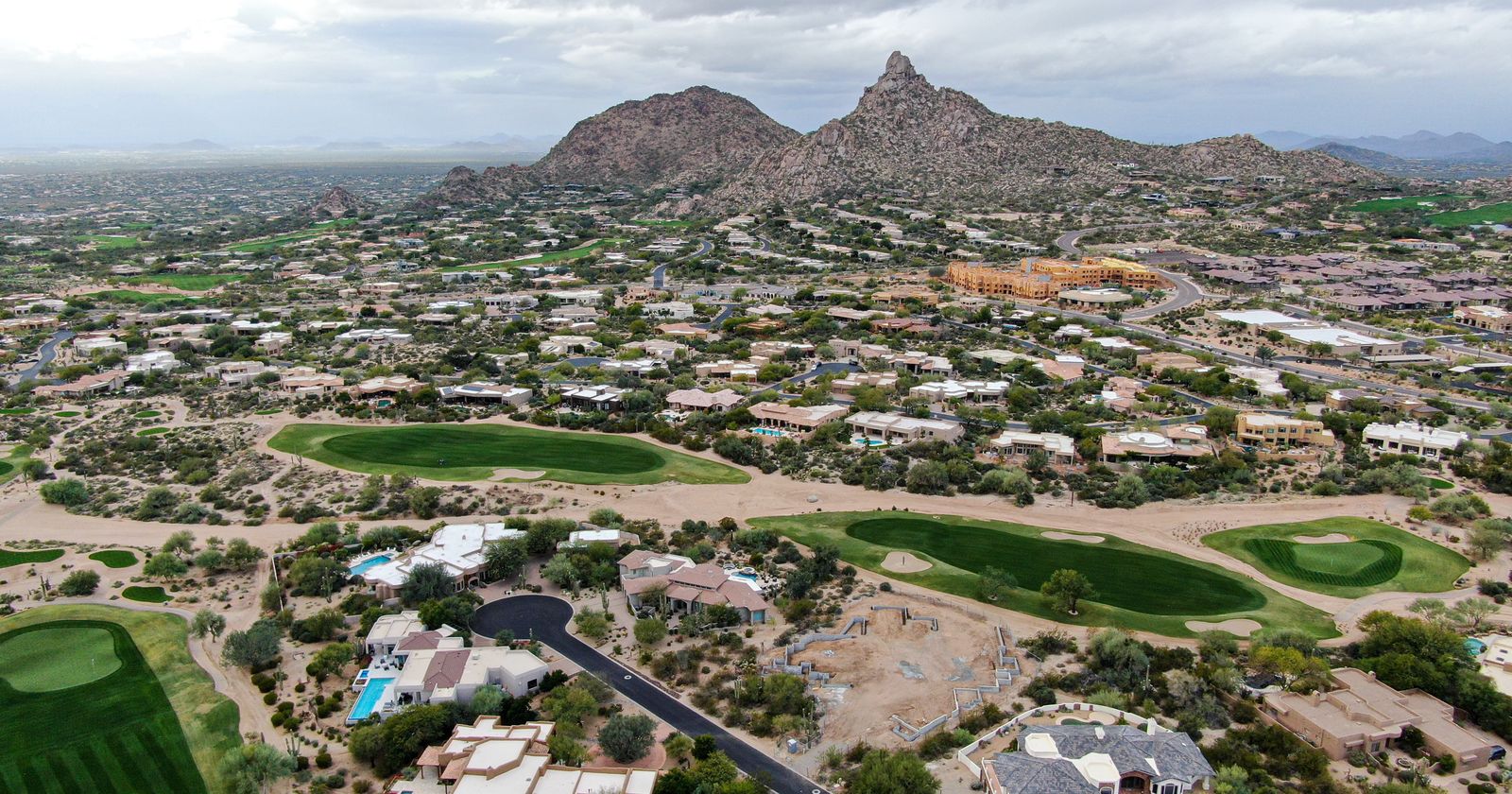 Aerial view of a desert golf-course community with a mountain peak beyond