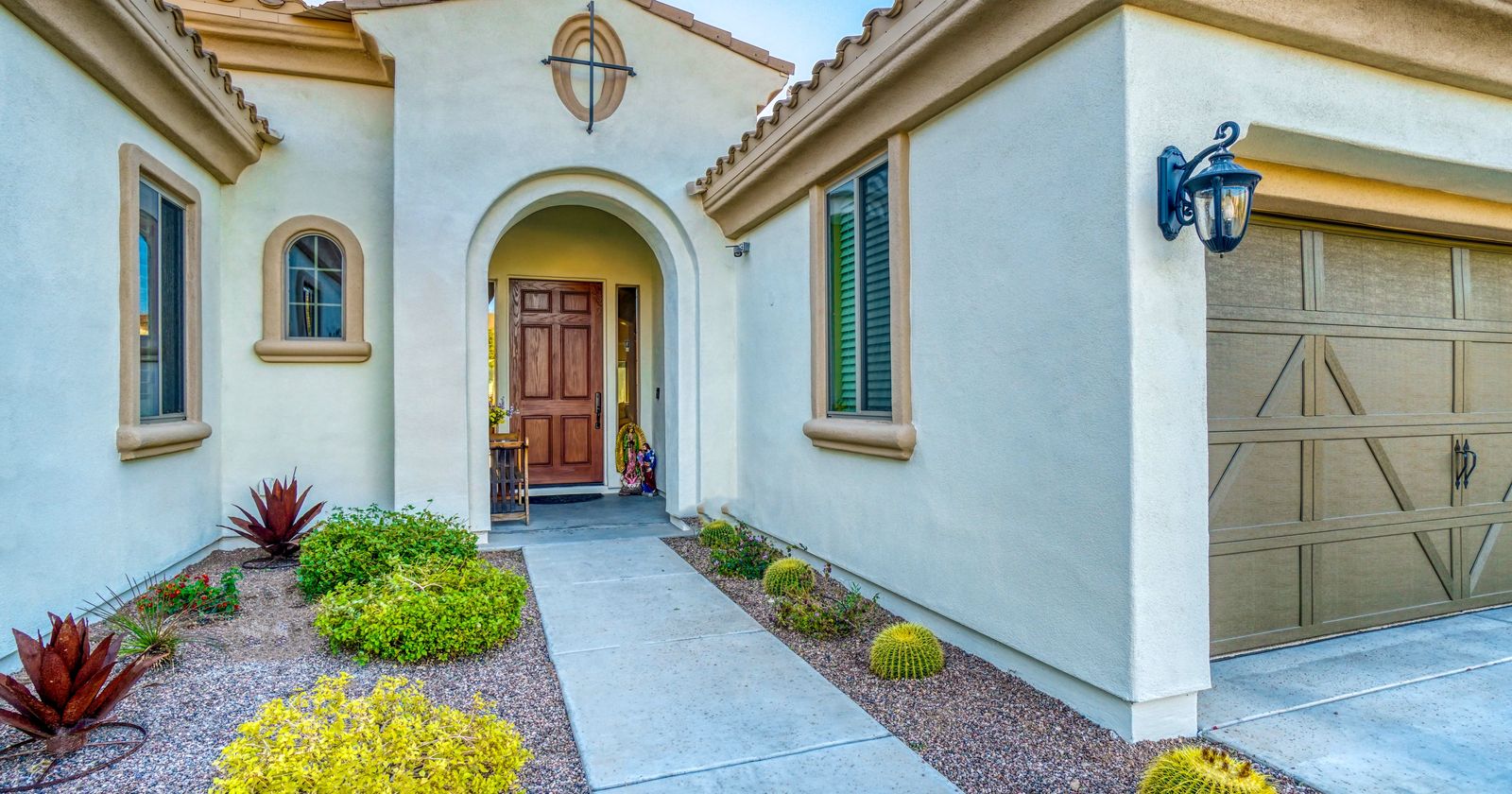 Front entrance of a stucco Southwestern home with desert landscaping