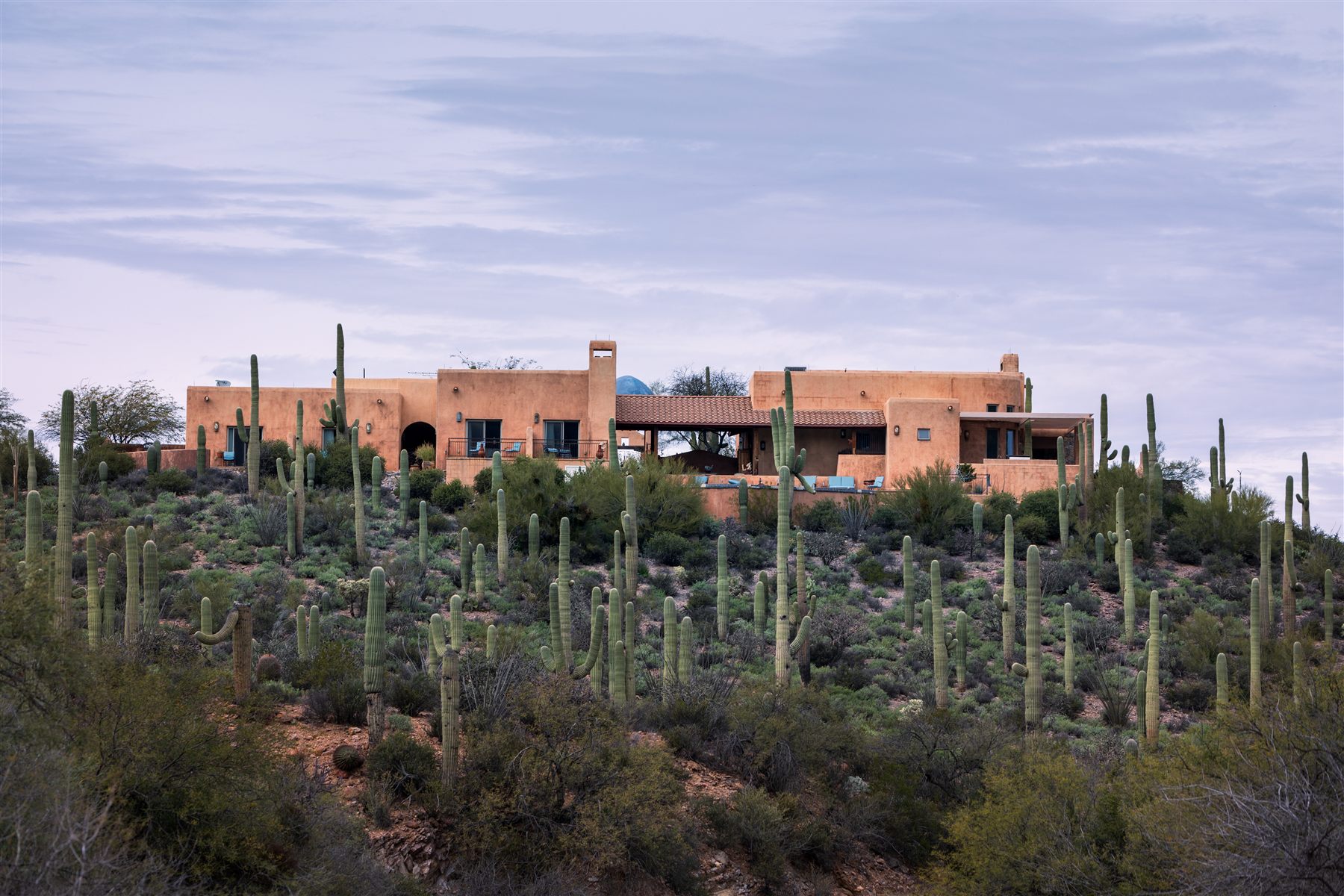 Adobe home on a saguaro-covered hillside in the Sonoran Desert