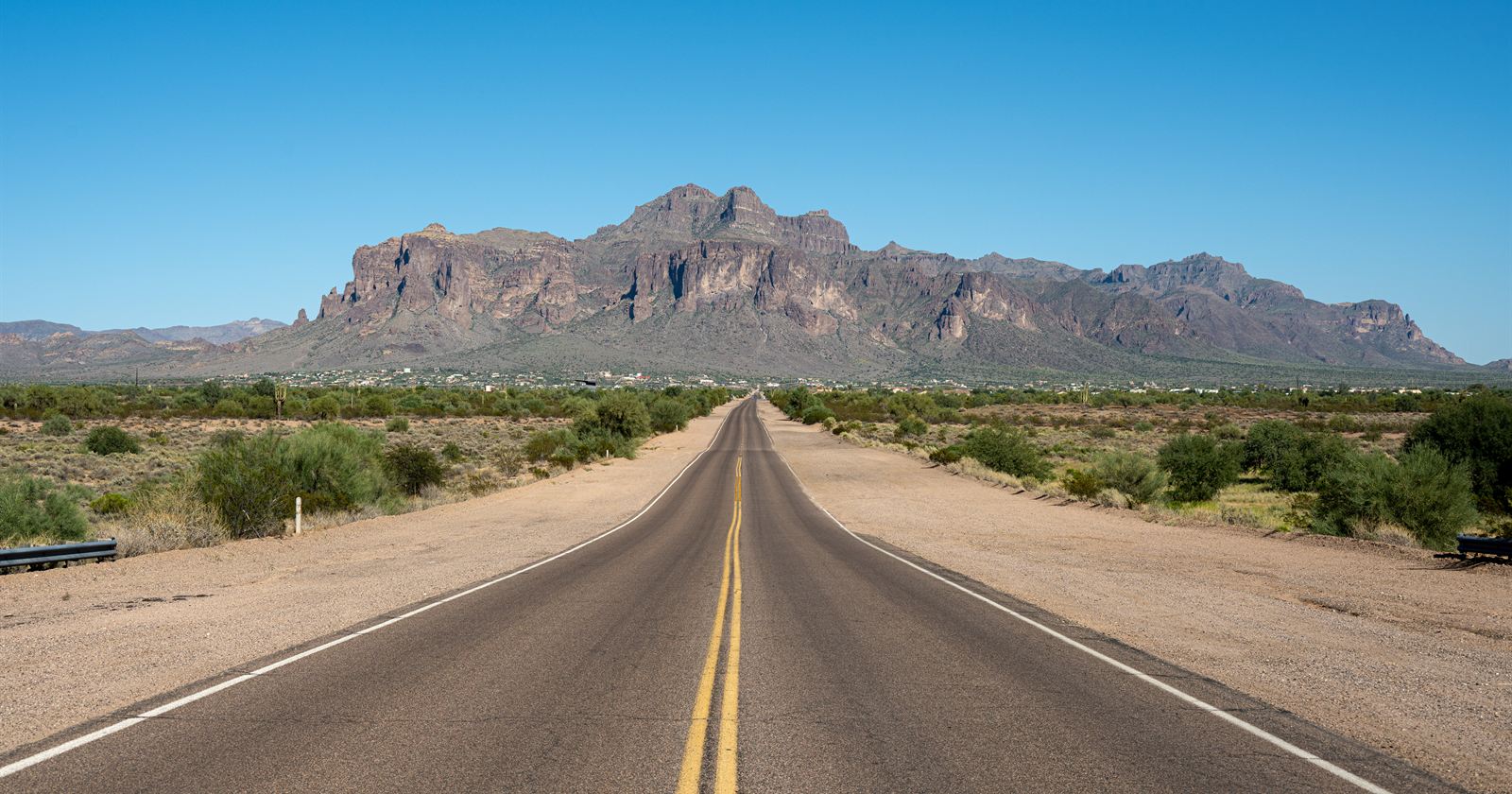 Straight desert highway leading toward rugged Arizona mountains on the last leg of the Minnesota to Arizona road trip